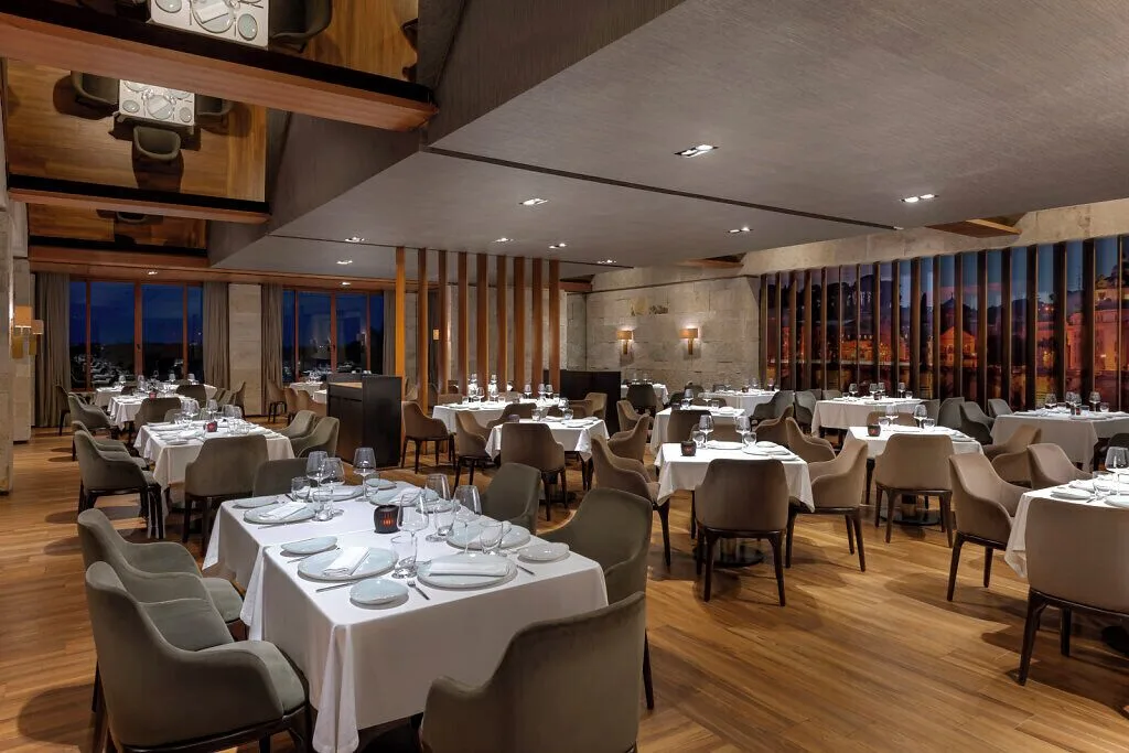 Large restaurant dining room with white linens and wood floors at Grand Velas Riviera Maya.