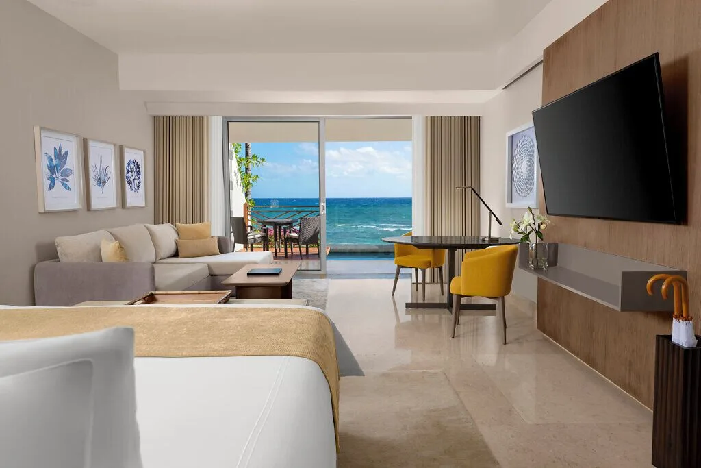 Grand Class Pool Suite with bed, sofa, desk, TV and oceanfront terrace at Grand Velas Riviera Maya.