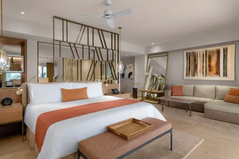 Grand Class Pool Suite king bed with sofa, bench, pendant lights and abstract art at Grand Velas Riviera Maya.