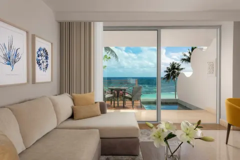 Grand Class Pool Suite sofa beside glass doors to a plunge pool and ocean at Grand Velas Riviera Maya.