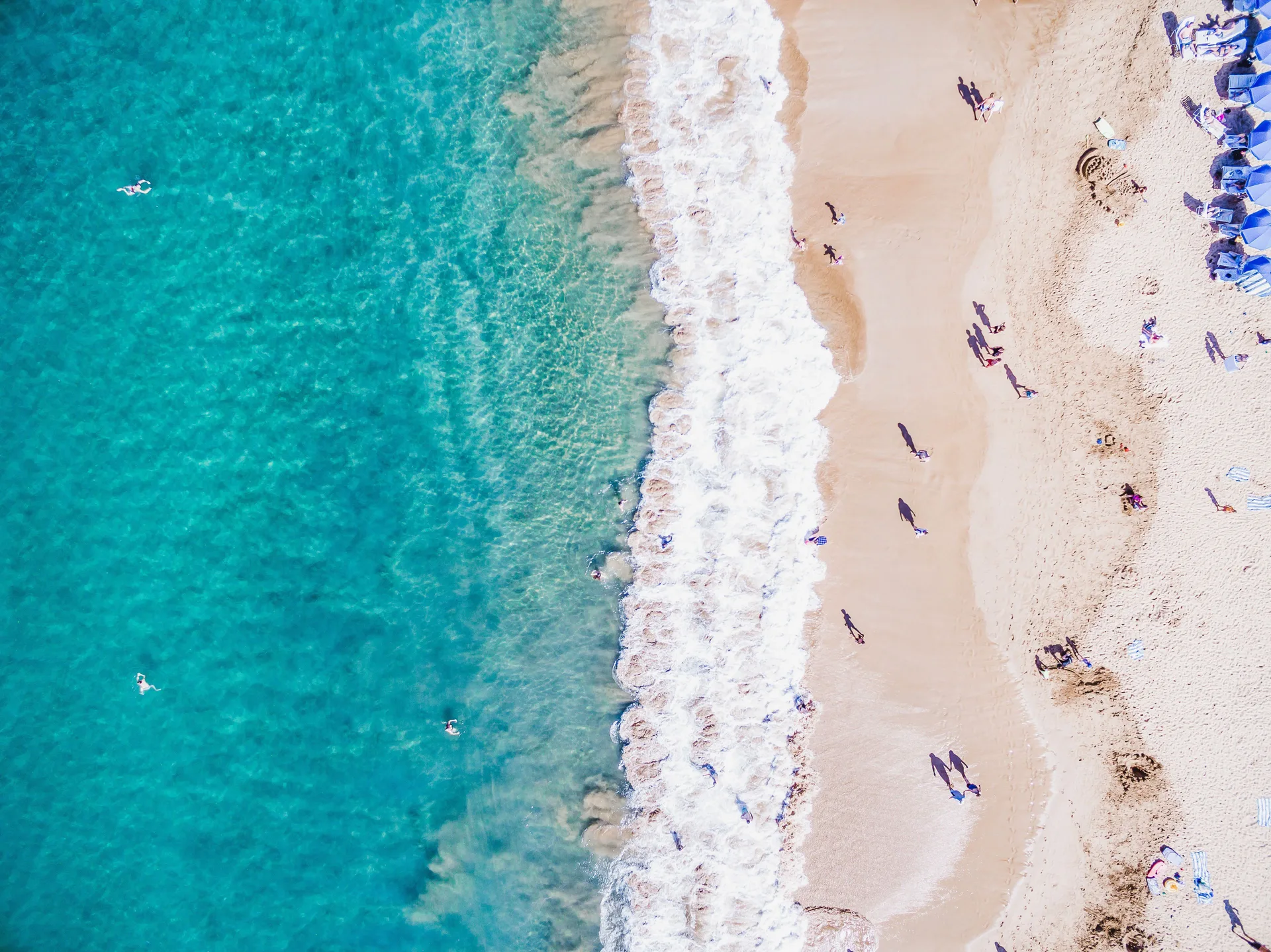 Aerial view of turquoise water, surf, and sandy beach at Grand Wailea Maui.