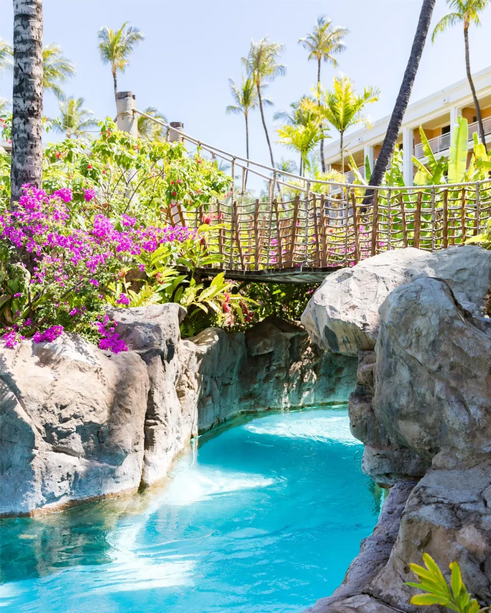 Garden pool channel with rocks, bridge and flowering plants at Grand Wailea Maui.