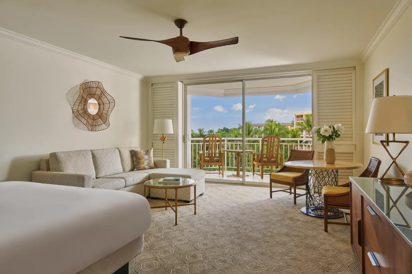 Guest room with bed, sofa, desk, and balcony view at Grand Wailea Maui.