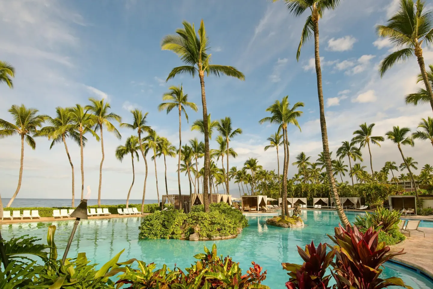 Palm-lined resort pool with ocean beyond at Grand Wailea Maui.