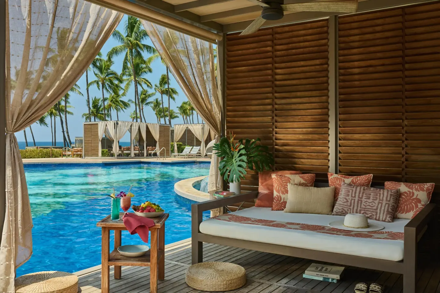 Poolside cabana with daybed, drinks, fruit and ocean palms at Grand Wailea Maui.