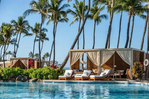 Poolside cabanas and lounge chairs beside the water at Grand Wailea Maui.