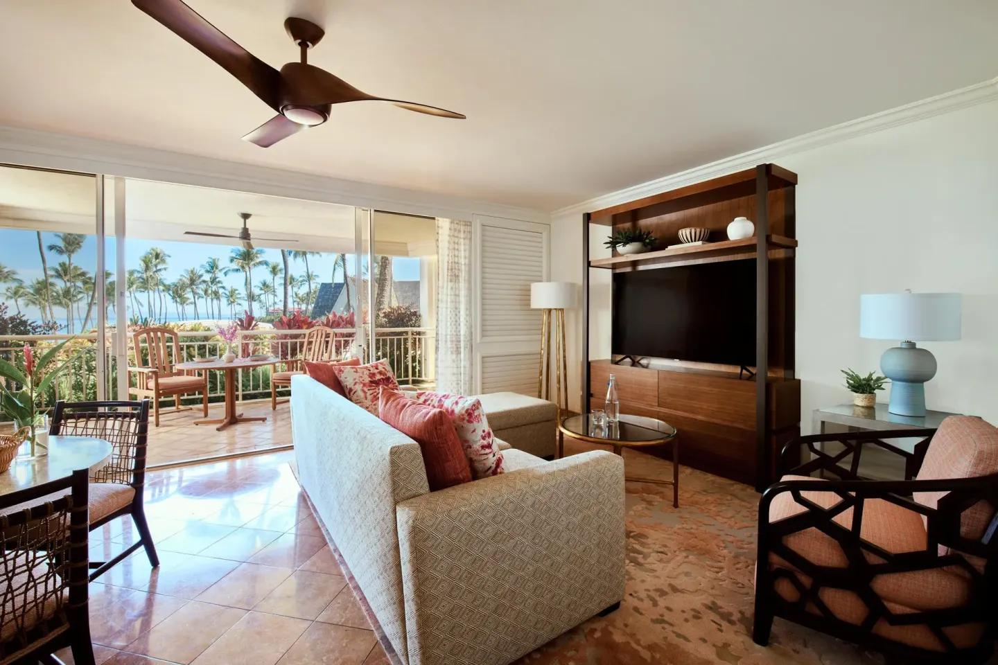 Suite living room with sofa, TV, dining table, and ocean-view lanai at Grand Wailea Maui.