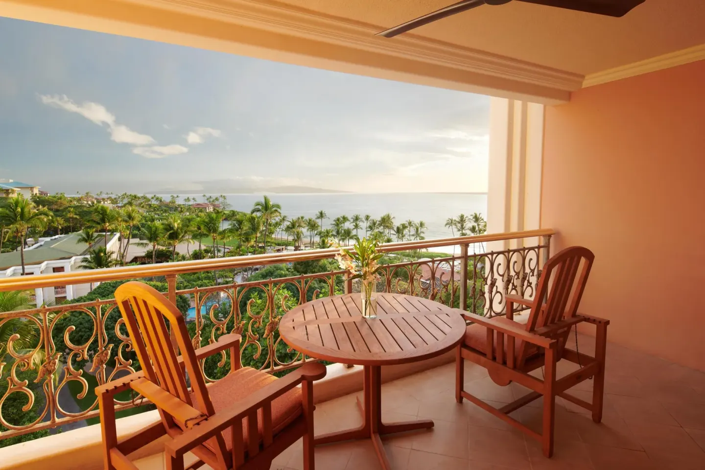Sunlit ocean-view balcony with wooden chairs at Grand Wailea Maui.