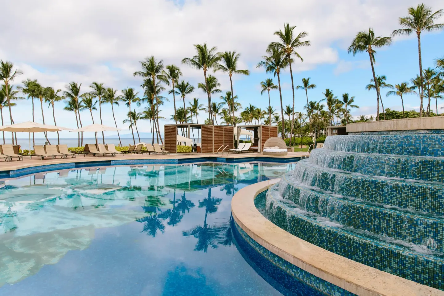 Tiered fountain beside a resort pool and cabanas at Grand Wailea Maui.