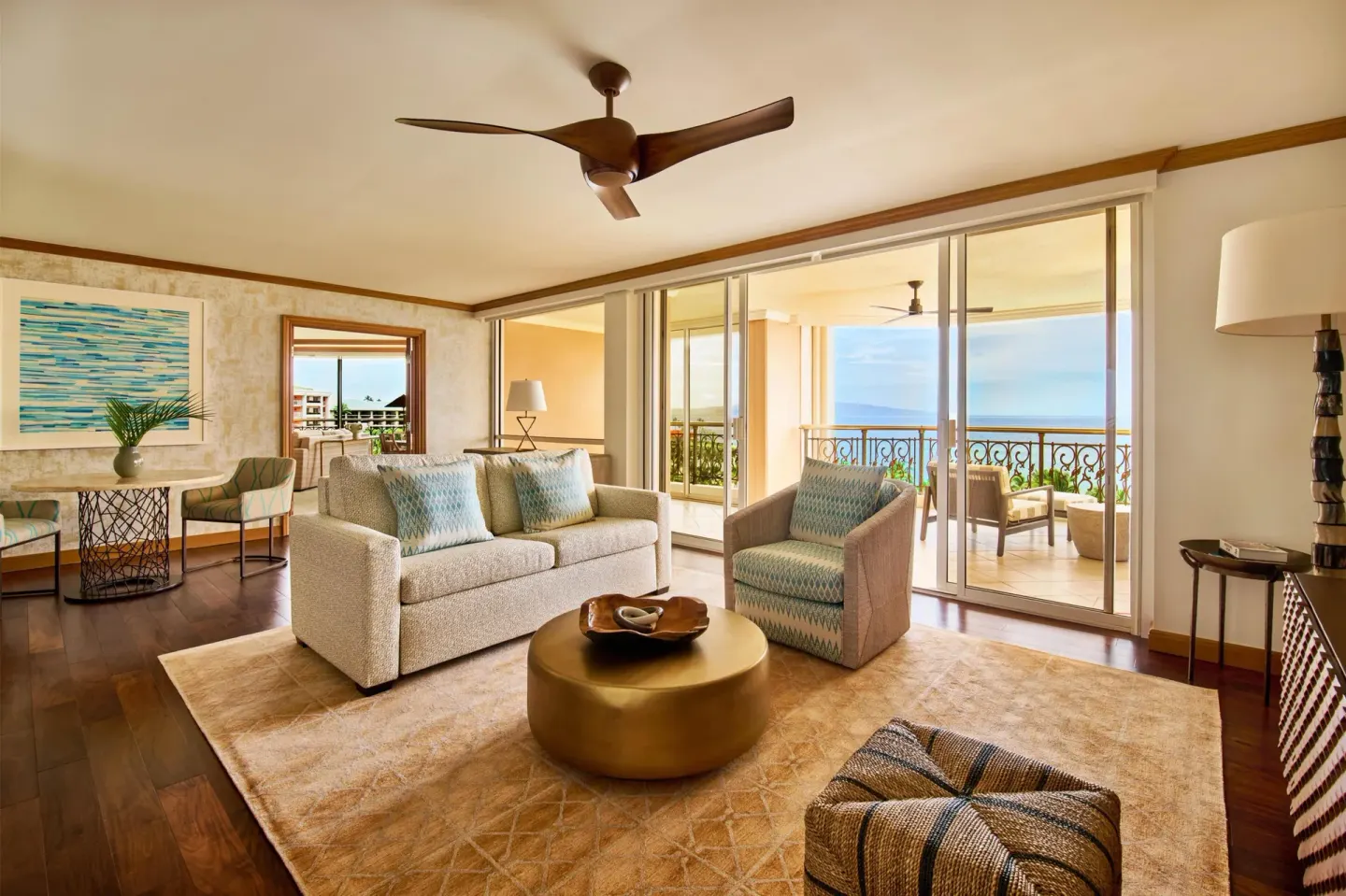 Napua Puakea Suite living room with sofa, balcony, and ocean view at Grand Wailea Maui.