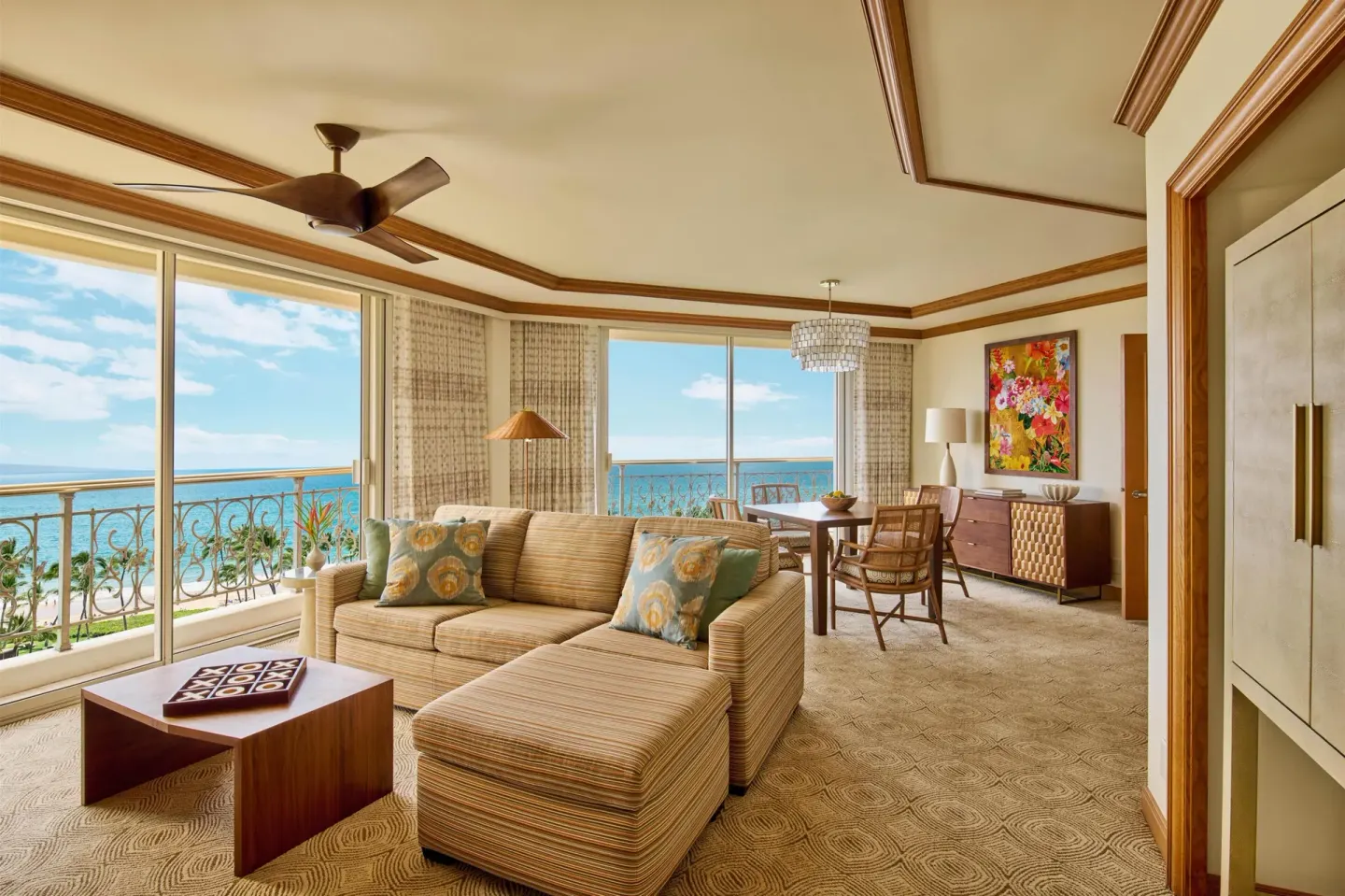 Napua Puakea Suite sitting and dining area with ocean-facing windows at Grand Wailea Maui.