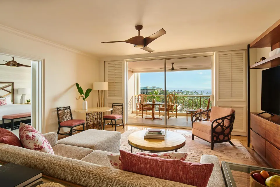 Living room of the Napua Nani ocean view suite at Grand Wailea Maui with balcony and bedroom beyond.