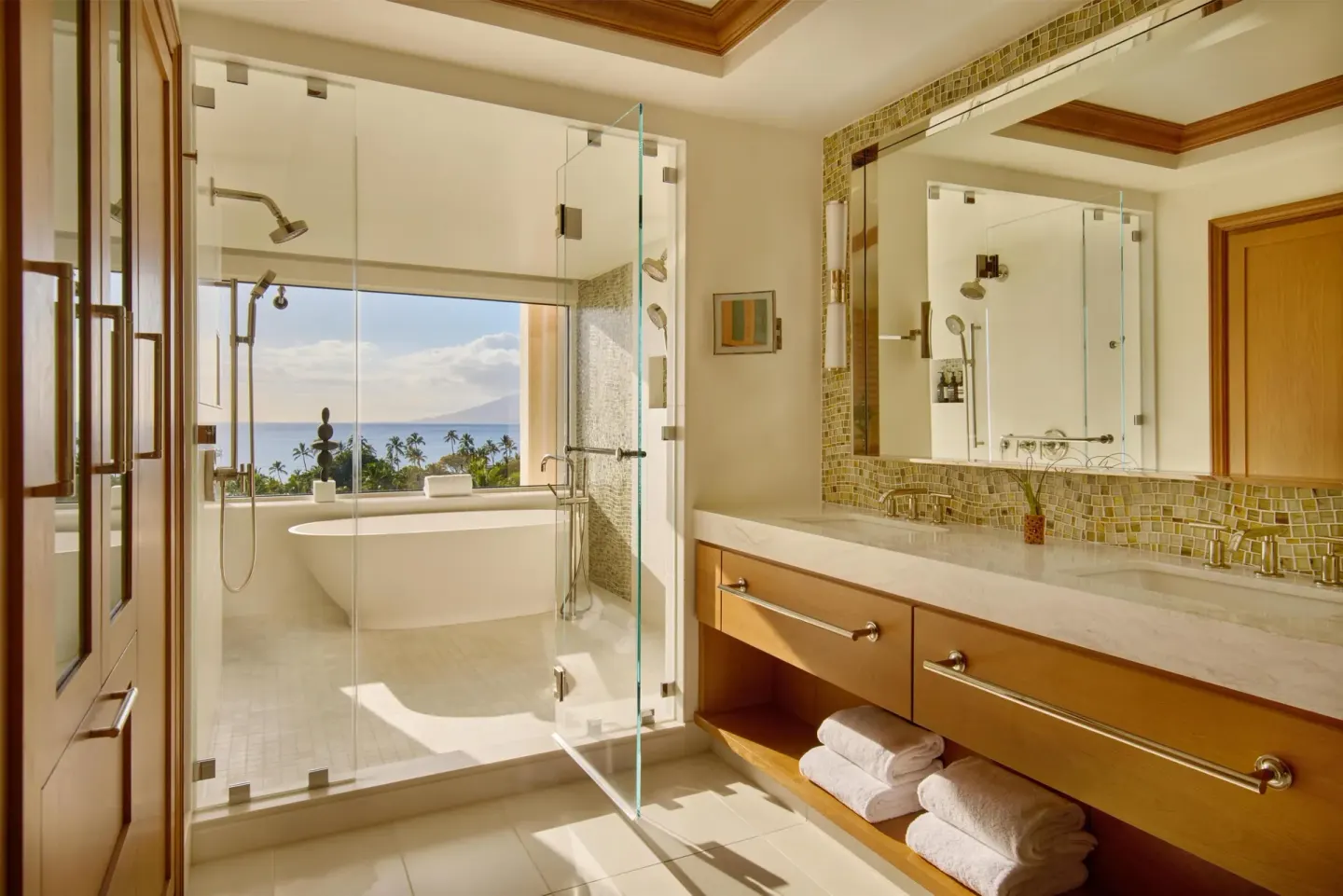 Napua Malu Suite bathroom with glass shower, tub, and ocean view at Grand Wailea Maui.