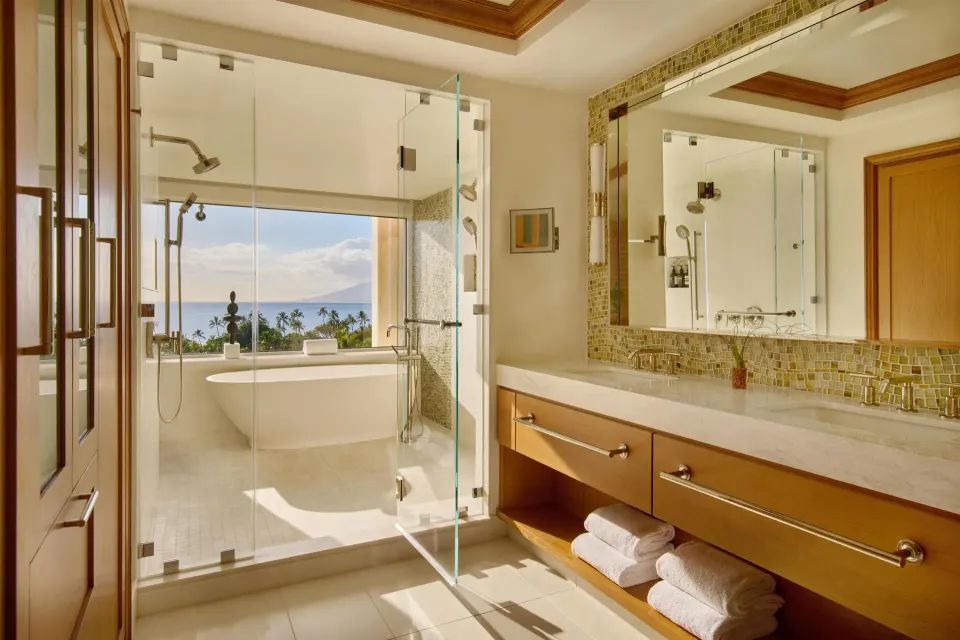 Napua Malu Suite bathroom with glass shower, tub, and ocean view at Grand Wailea Maui.