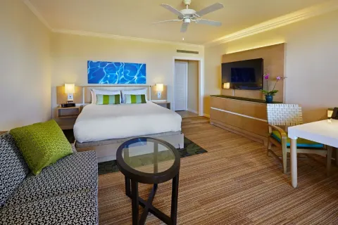 Deluxe Room Ocean View king bed with sofa, TV and desk at Grand Wailea Maui.
