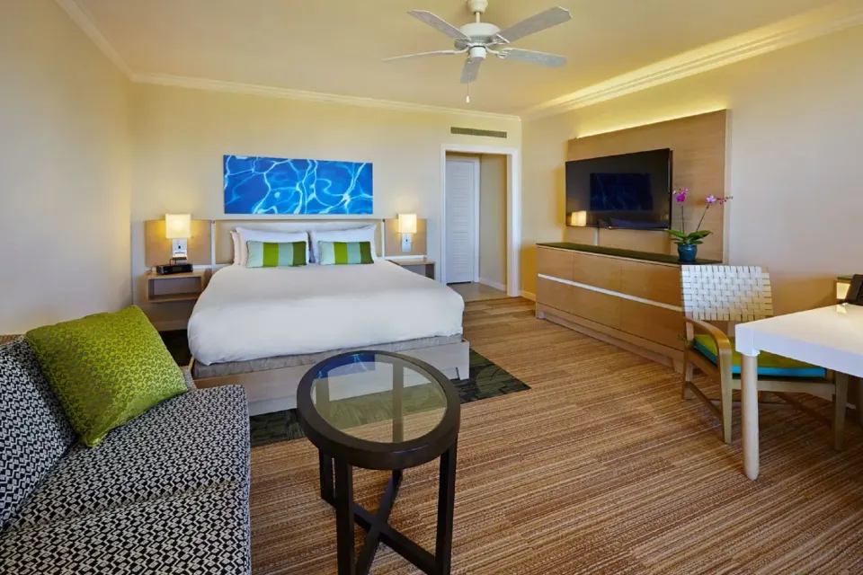 Deluxe Room Ocean View king bed with sofa, TV and desk at Grand Wailea Maui.