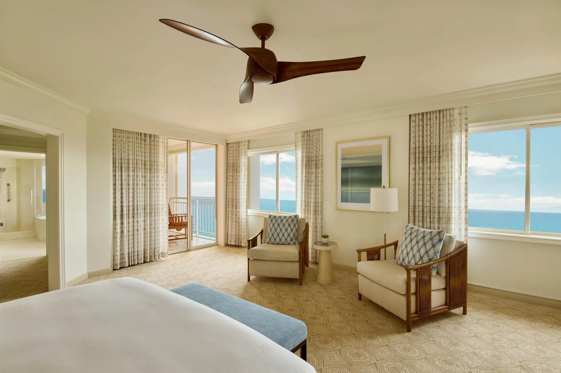 Bedroom in a Deluxe Suite at Grand Wailea Maui with ocean views, seating area and balcony access.