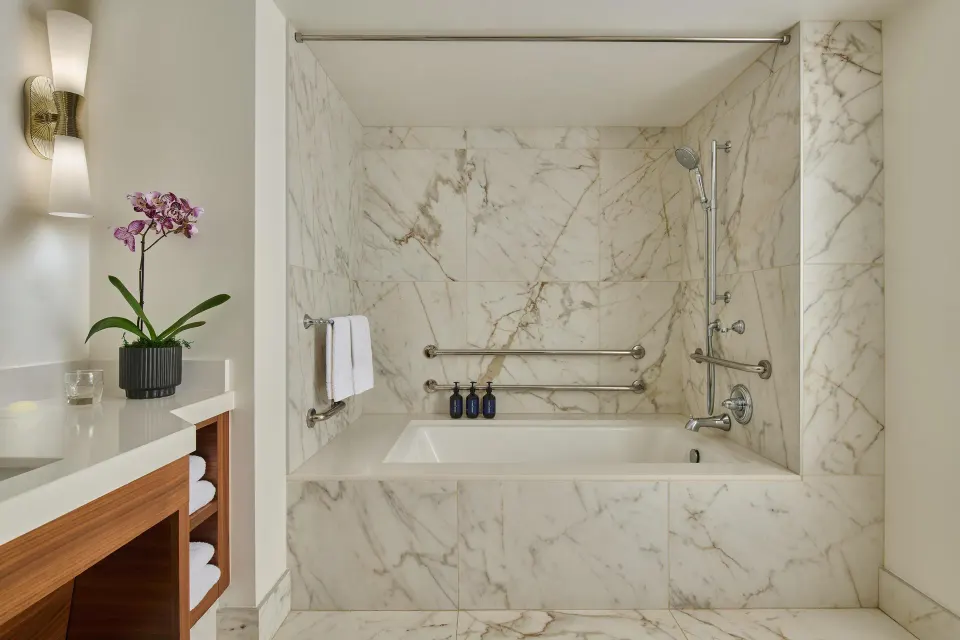 Accessible marble bathtub with grab bars in a guest room bathroom at Grand Wailea Maui.