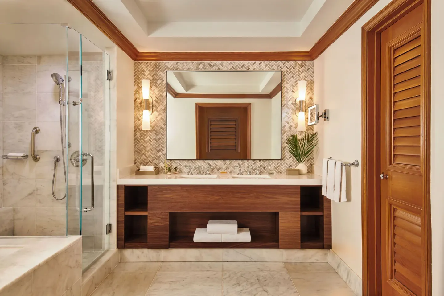Royal Suite bathroom with glass shower, double vanity, and wood shutters at Grand Wailea Maui.