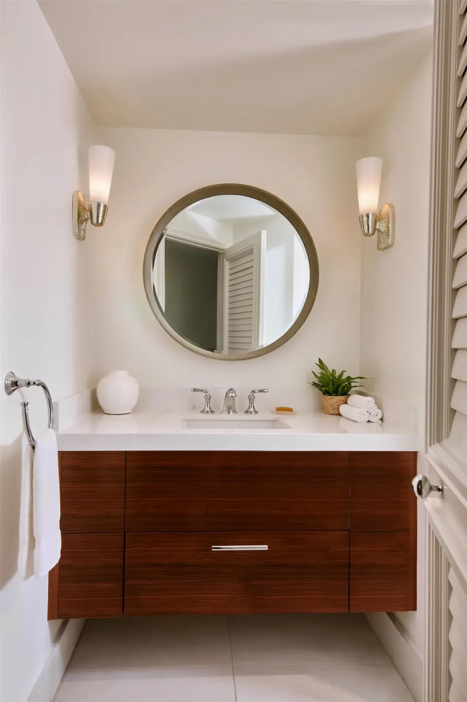 Bathroom vanity in a one-bedroom garden view suite at Grand Wailea Maui with round mirror and sconces.