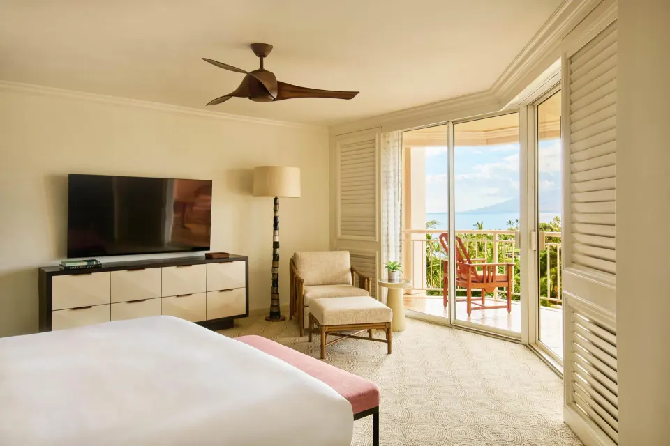 Bedroom in a garden view one-bedroom suite at Grand Wailea Maui with balcony doors and ocean beyond.