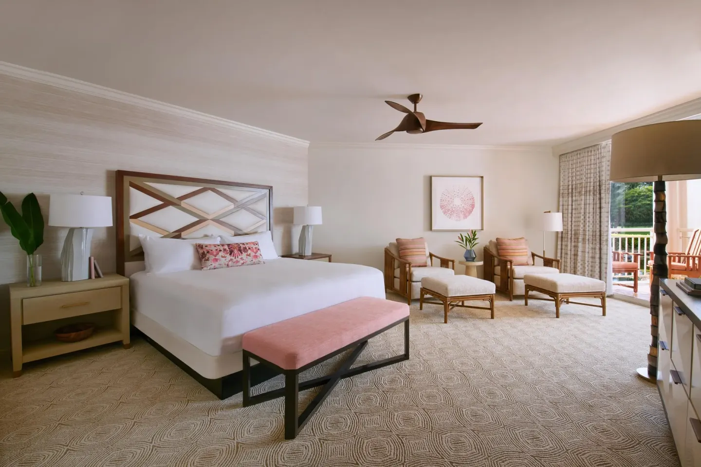 King bedroom in a one-bedroom garden view suite at Grand Wailea Maui with sitting area and balcony.