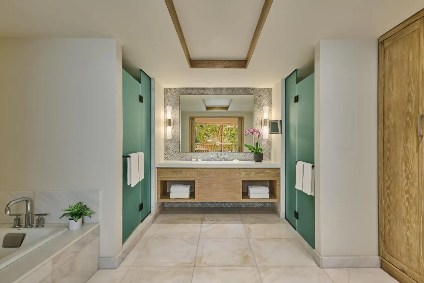 Suite bathroom with double vanity, soaking tub, and frosted doors at Grand Wailea Maui.