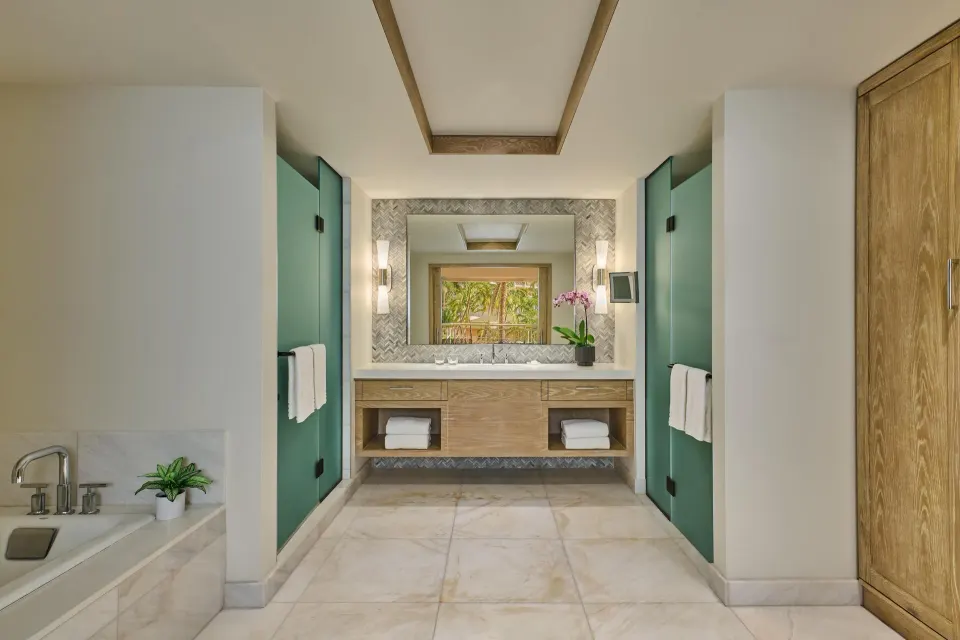 Suite bathroom with double vanity, soaking tub, and frosted doors at Grand Wailea Maui.