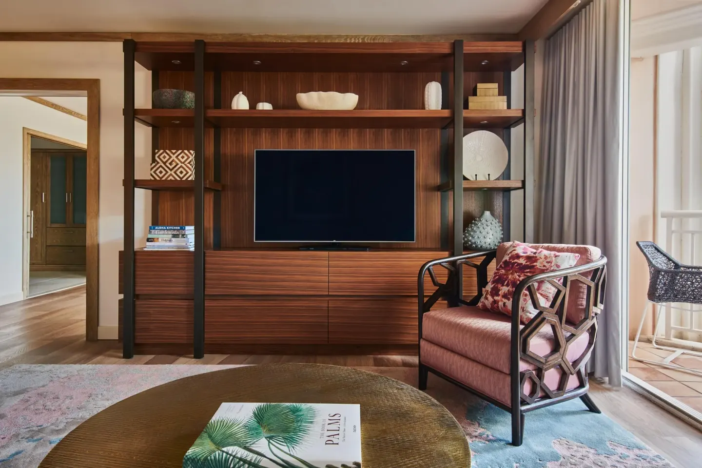 Garden view suite living room with media wall and balcony at Grand Wailea Maui.