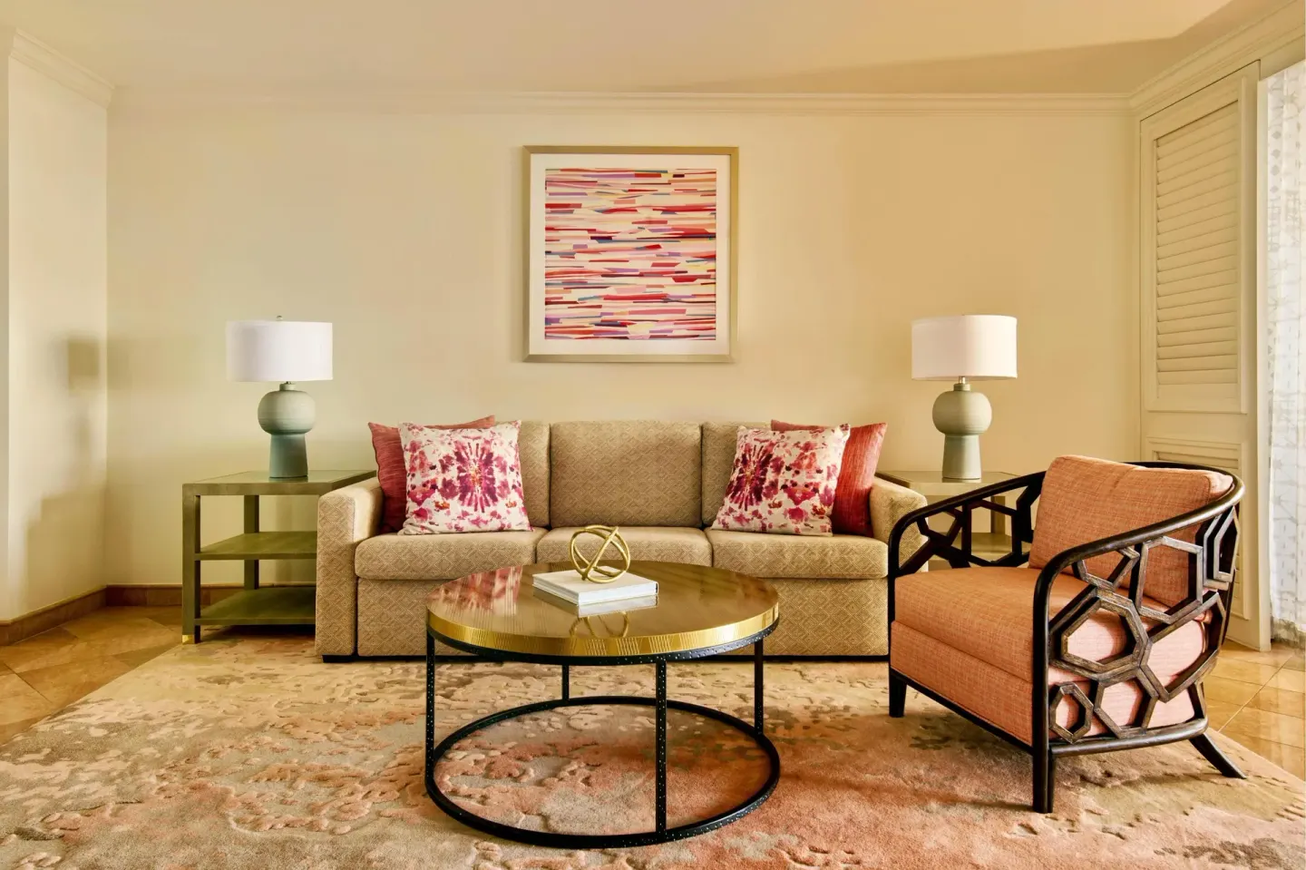 Seating area with sofa, armchair, round coffee table, lamps, and wall art at Grand Wailea Maui.