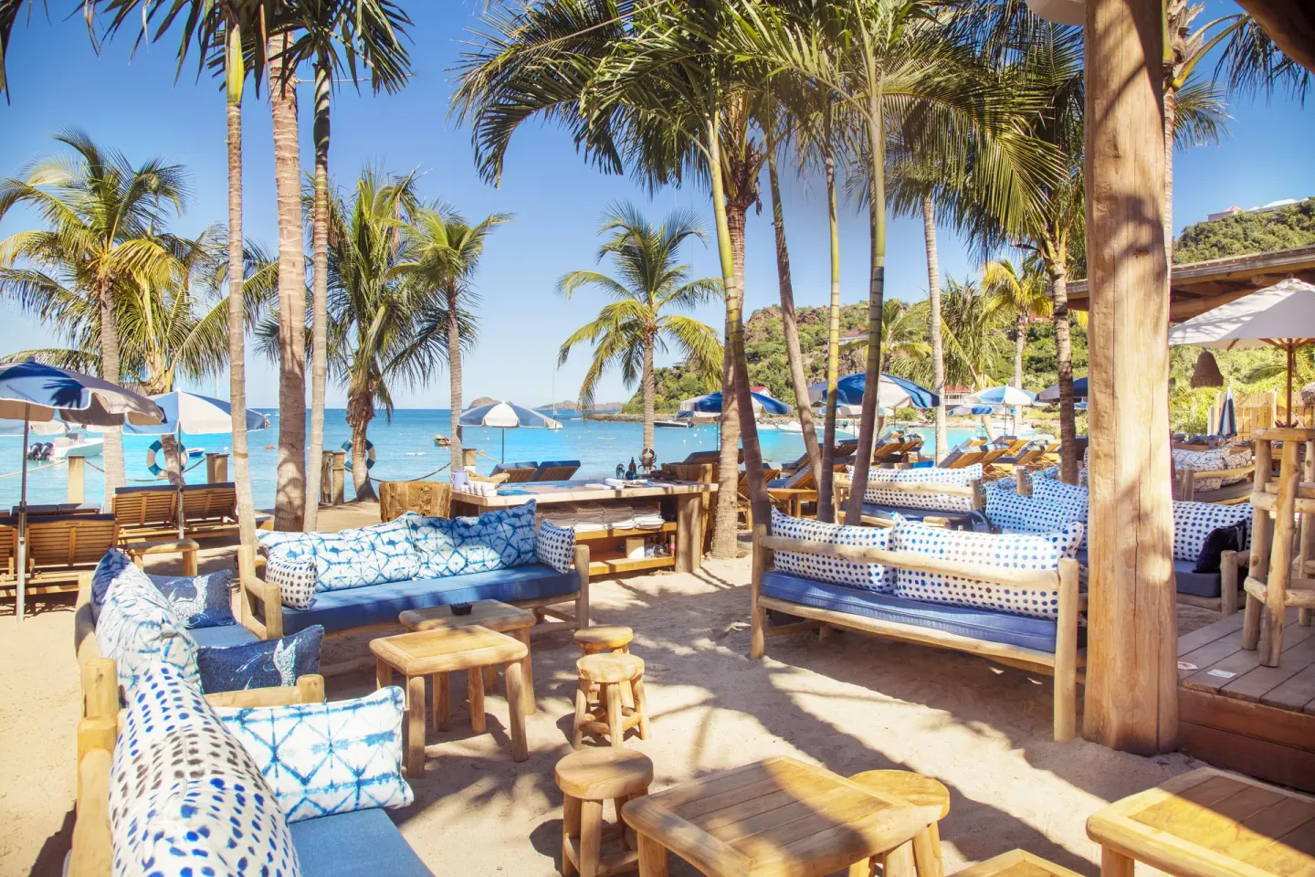 Beach lounge seating beneath palm trees at GYP SEA Saint Barth.