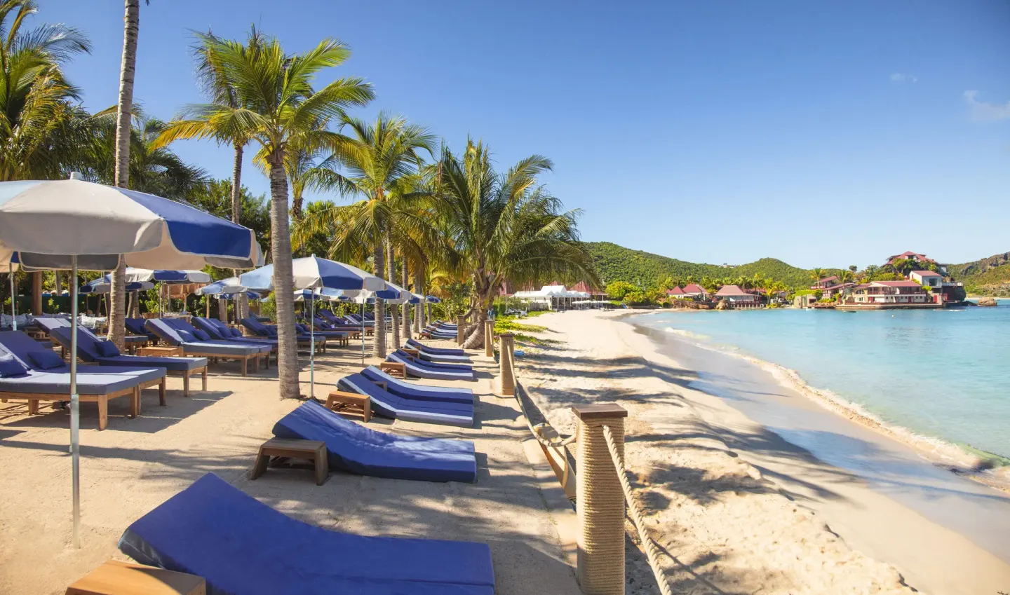 Beach loungers and umbrellas along the shore at GYP SEA Saint Barth.