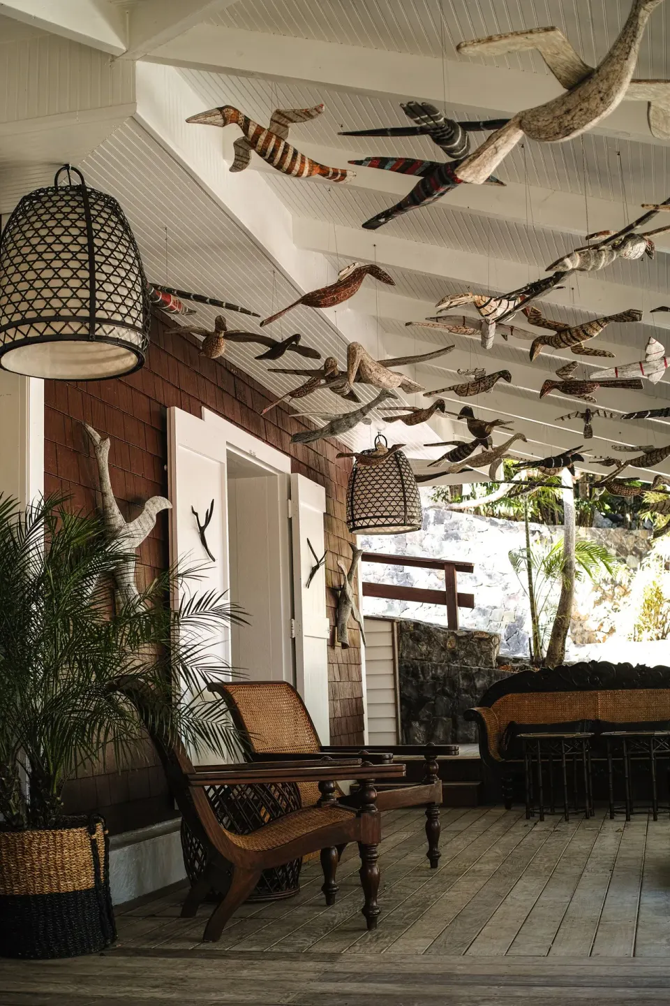 Covered veranda with wicker seating and bird sculptures at GYP SEA Saint Barth.