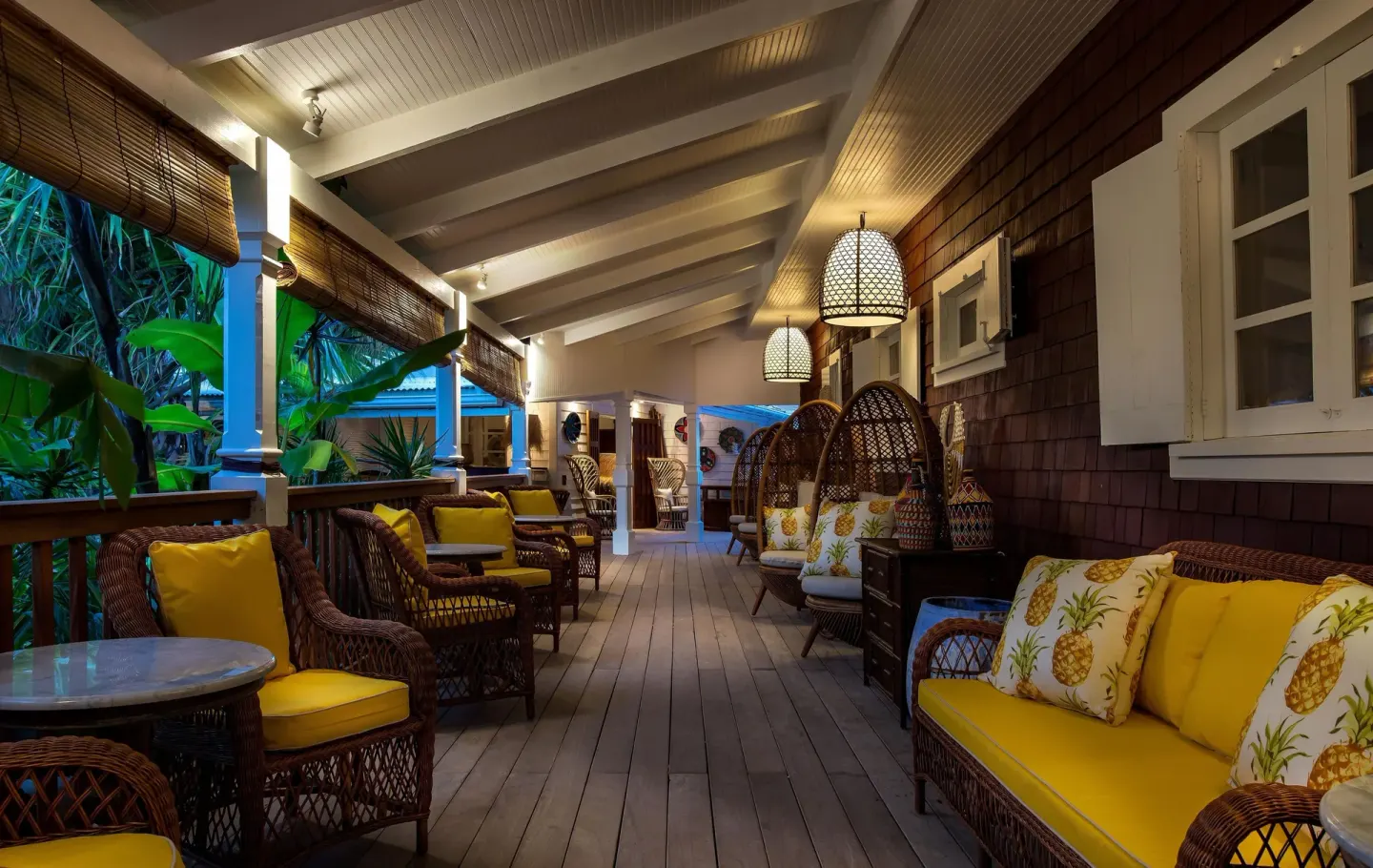 Evening veranda lounge with wicker seating and yellow cushions at GYP SEA Saint Barth.