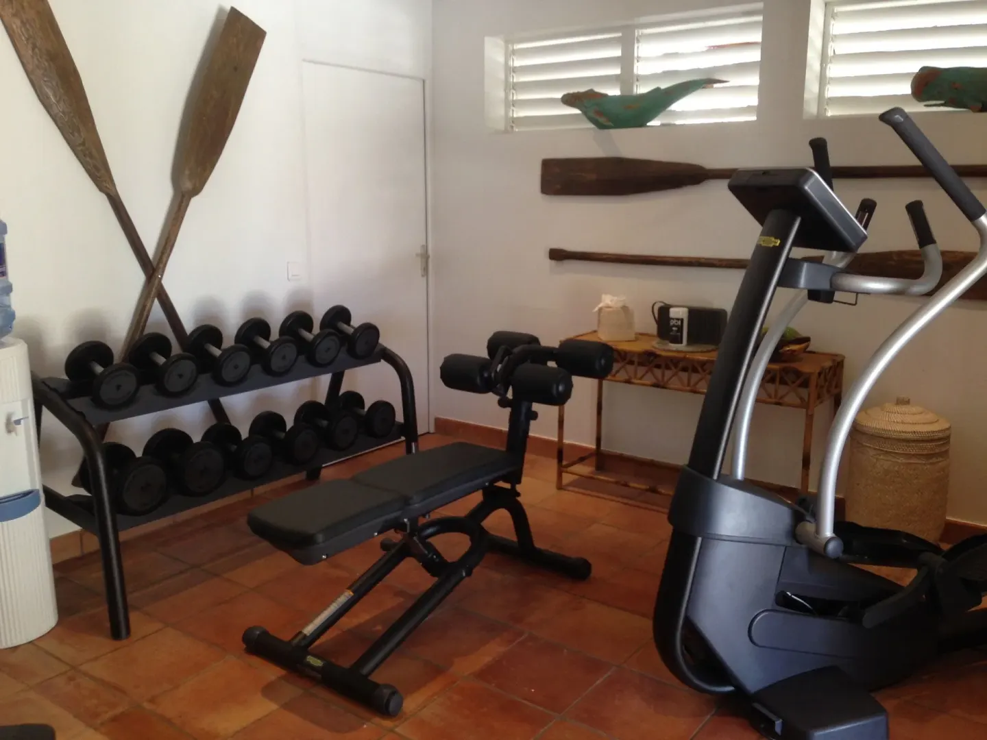 Fitness room with dumbbells, bench, and cardio machine at GYP SEA Saint Barth.