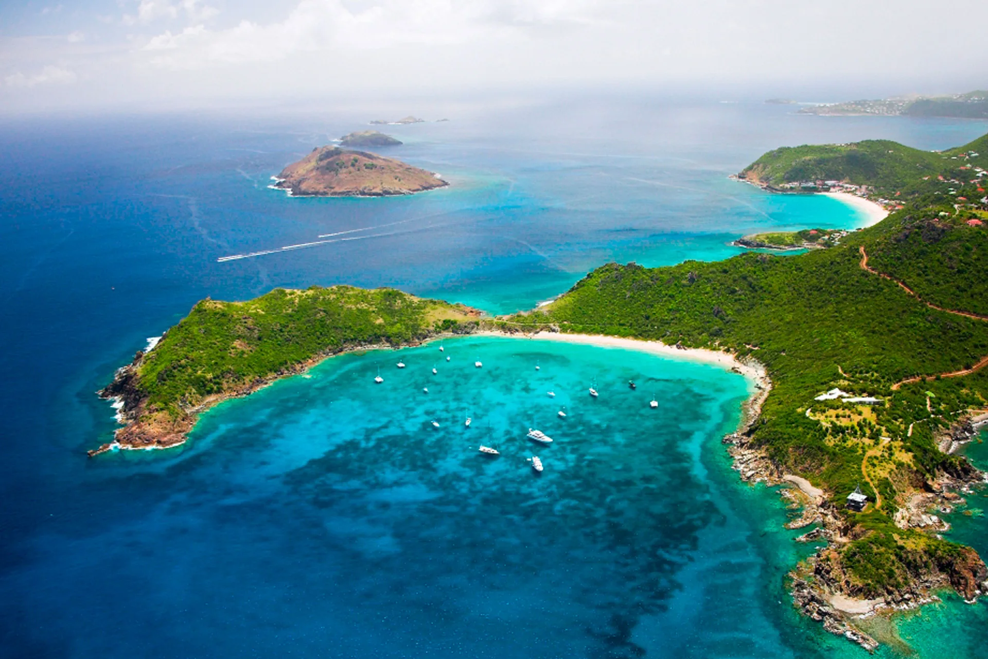 Aerial view of turquoise bays, boats, and green coastline near GYP SEA Saint Barth.