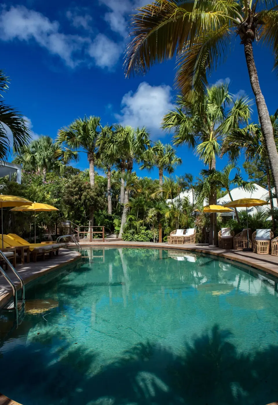 Palm-lined swimming pool with yellow umbrellas at GYP SEA Saint Barth.