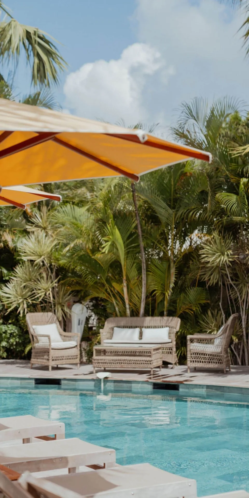 Pool with wicker seating, umbrellas, and tropical plants at GYP SEA Saint Barth.