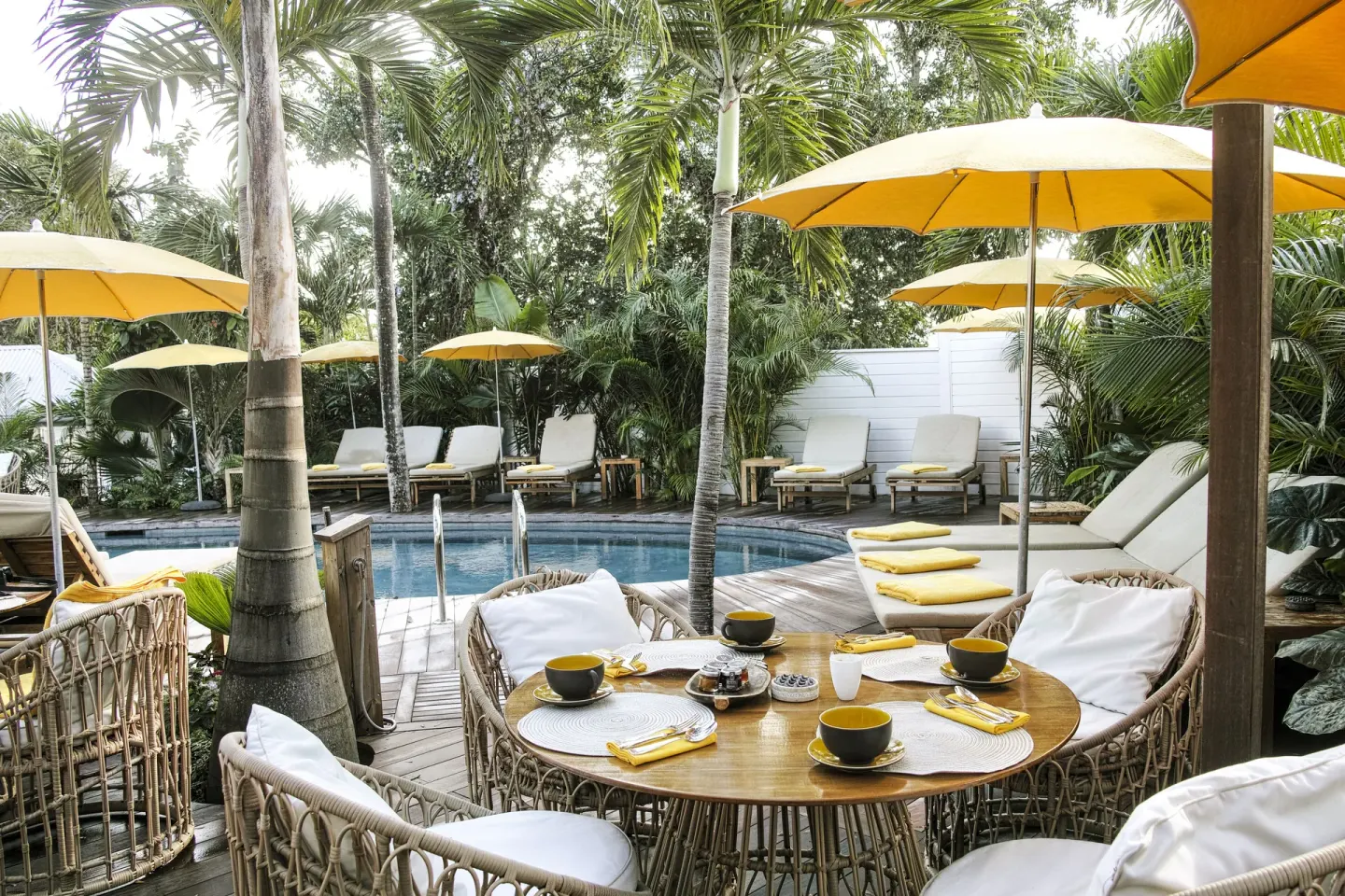 Poolside breakfast table with yellow umbrellas and loungers at GYP SEA Saint Barth.