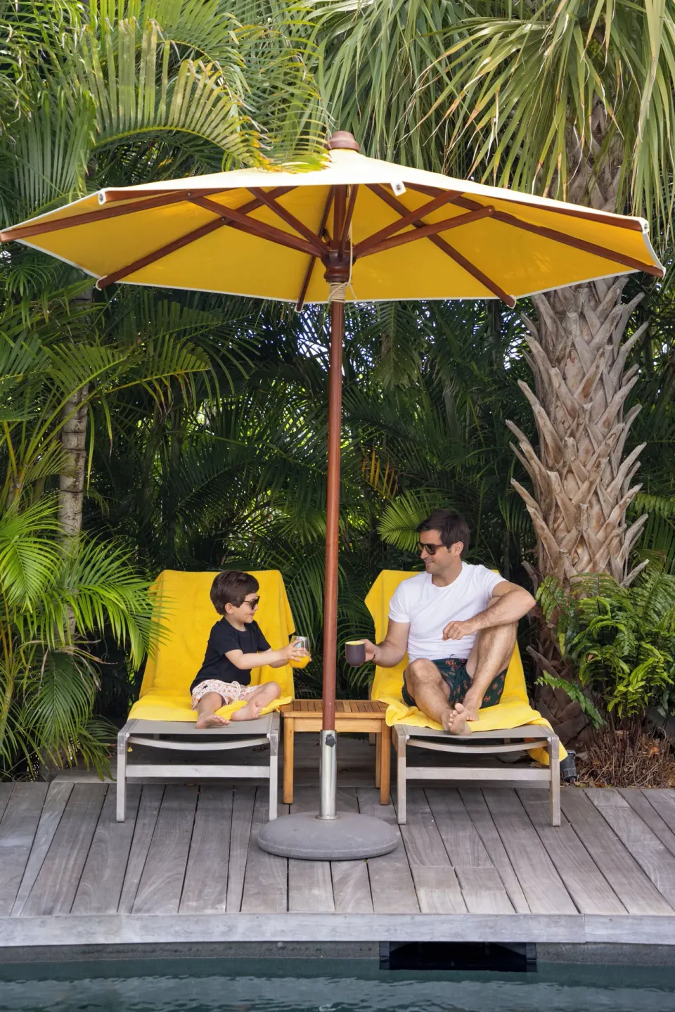 Adult and child on yellow loungers beside the pool at GYP SEA Saint Barth.