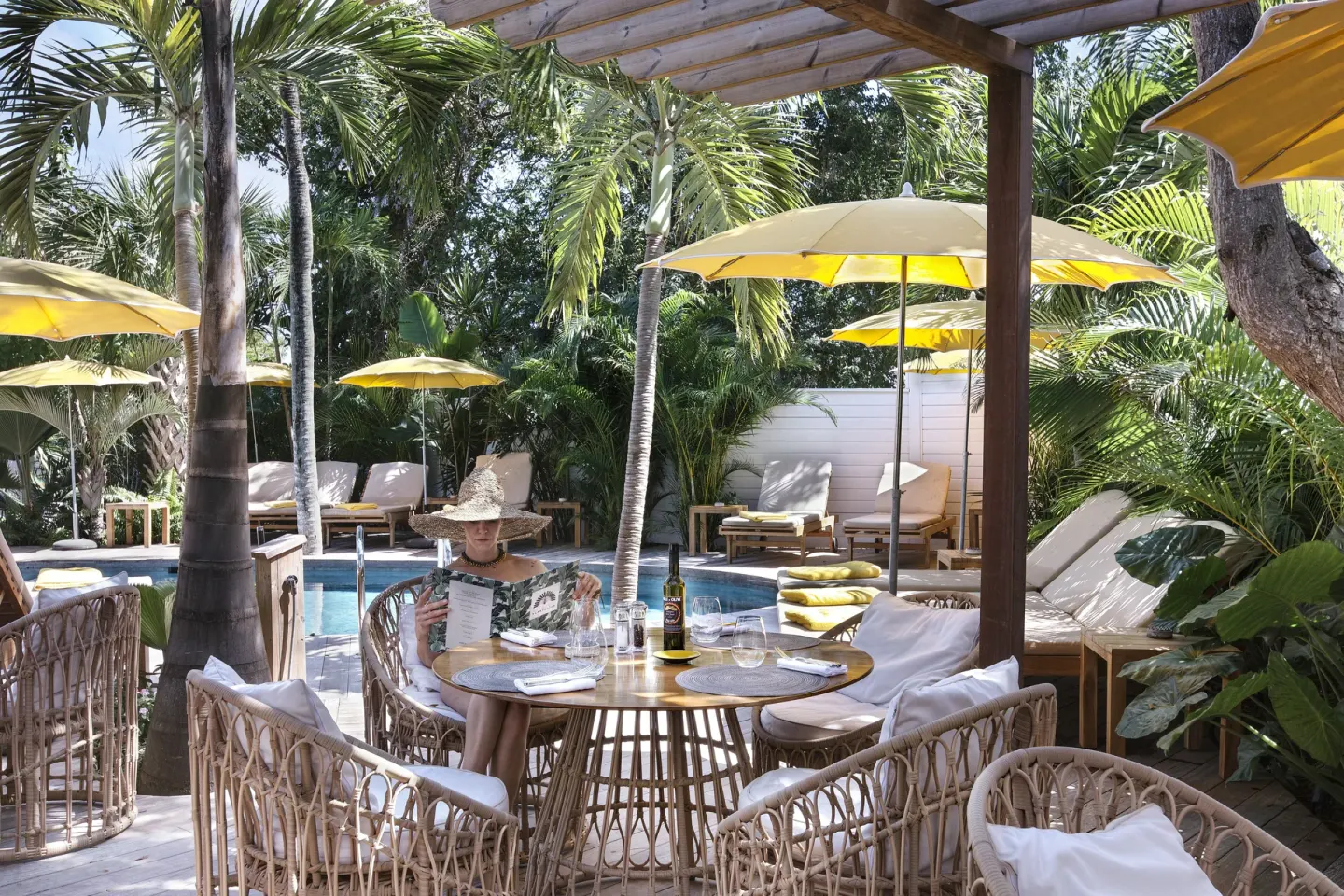 Poolside terrace with wicker chairs and yellow umbrellas at GYP SEA Saint Barth.