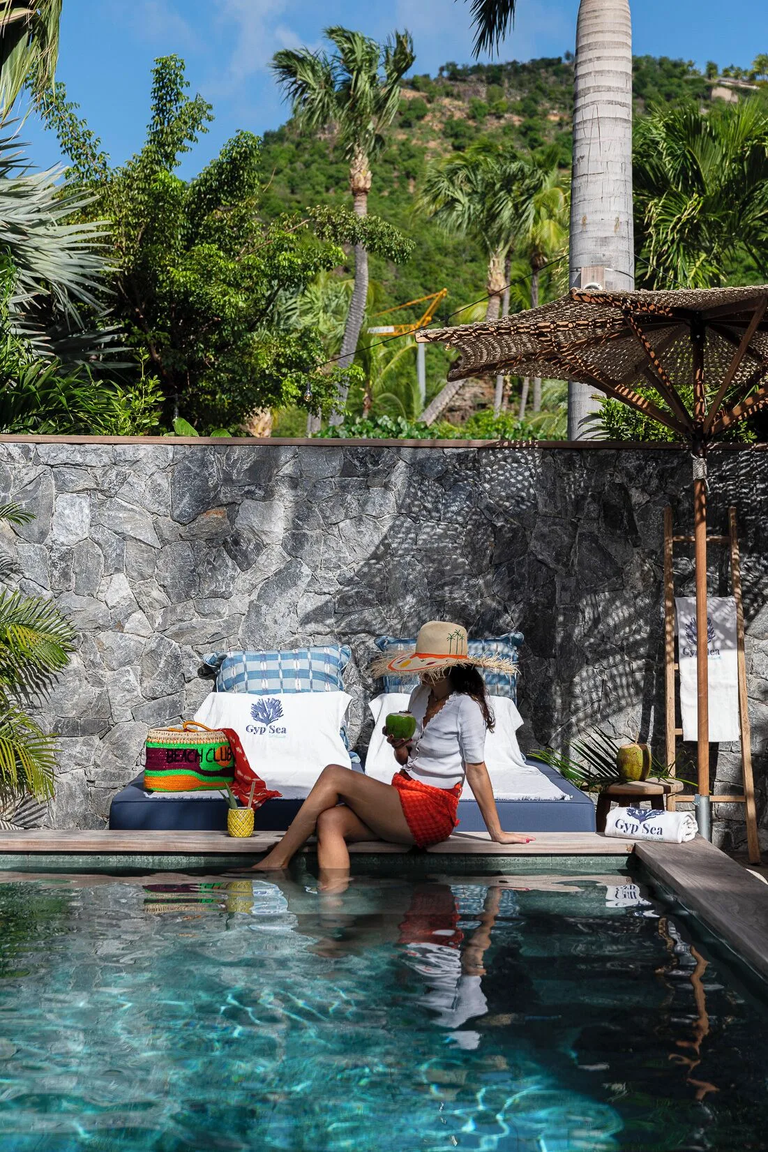 Guest seated by a private pool with tropical greenery at GYP SEA Saint Barth.