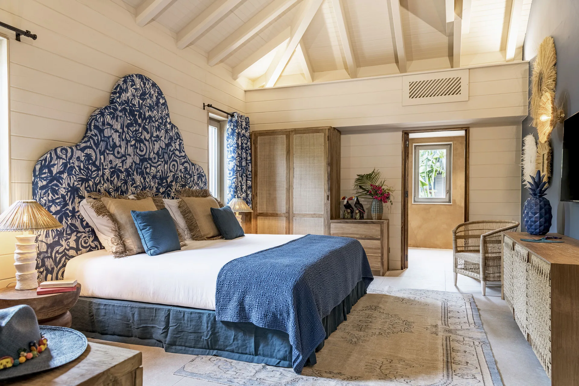 Bohemian Blue Beach House bedroom with king bed, blue headboard, and woven furniture at GYP SEA Saint Barth.