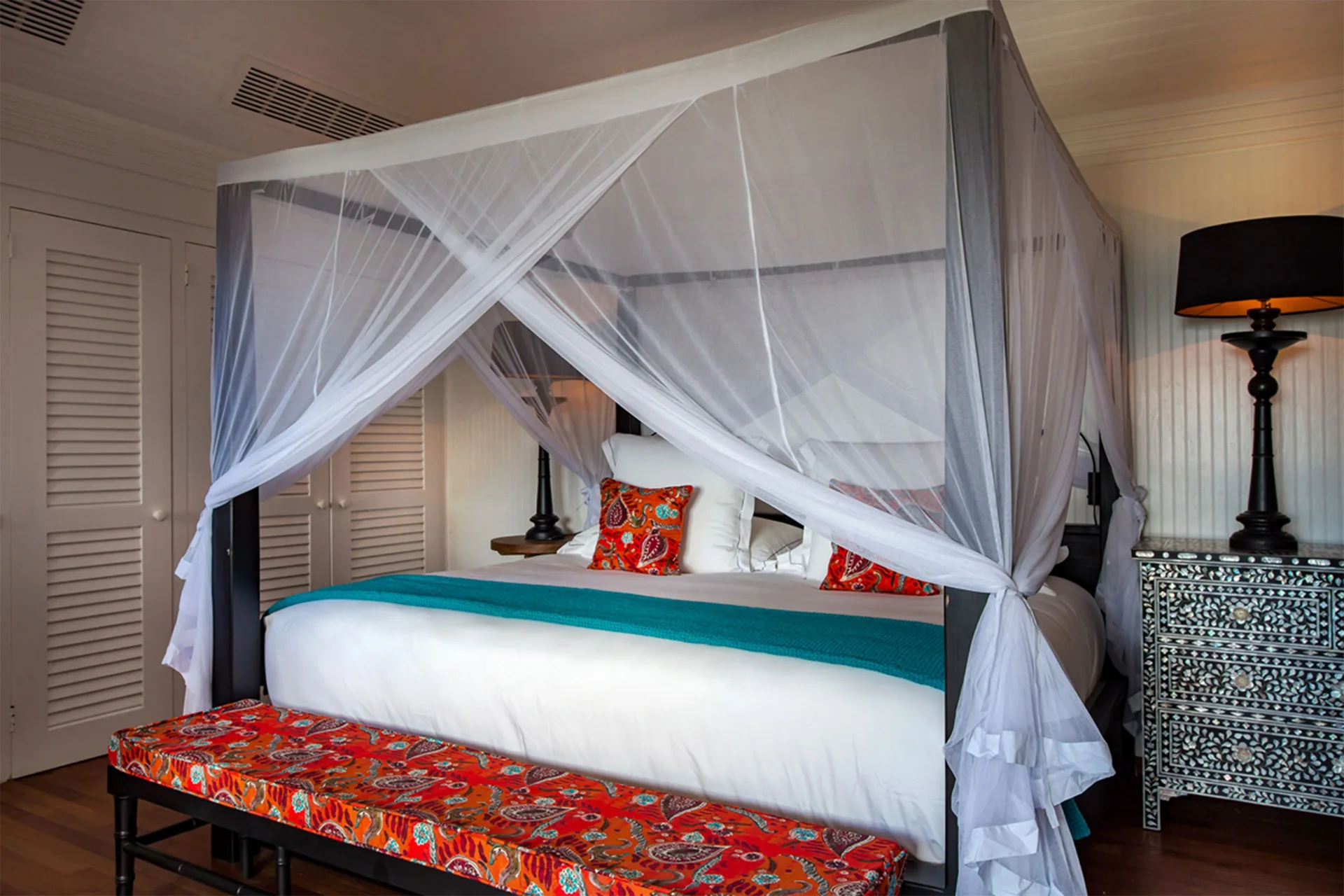 Caribbean Bungalow canopy bed beside louvered doors at GYP SEA Saint Barth.