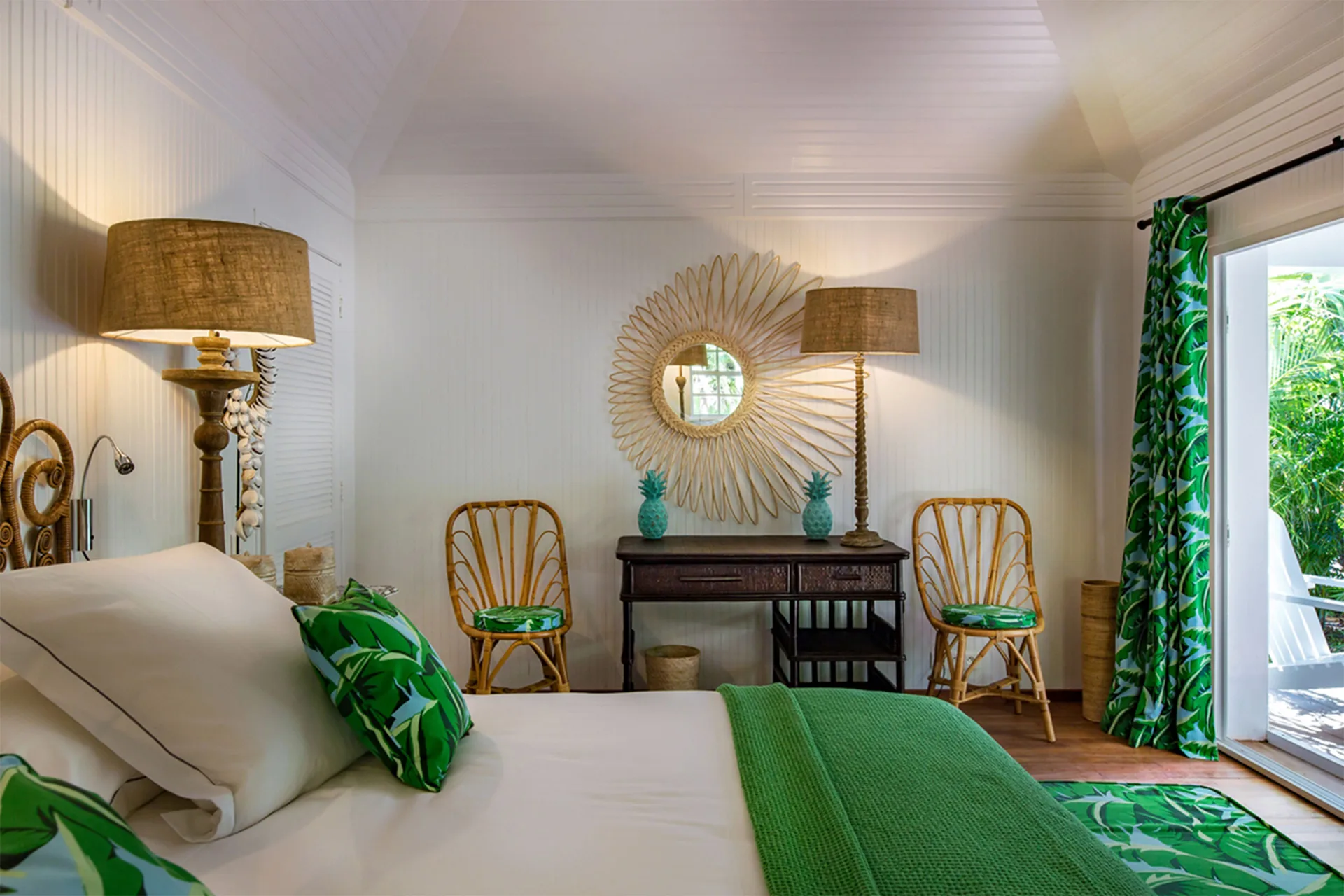 Bungalow king bed with green throw, rattan chairs, and terrace at GYP SEA Saint Barth.