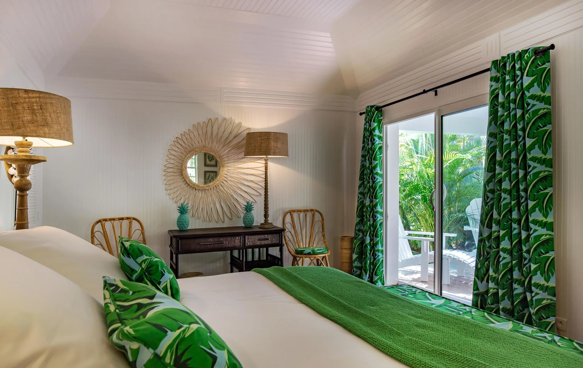 Bungalow king bed with green textiles and patio doors at GYP SEA Saint Barth.