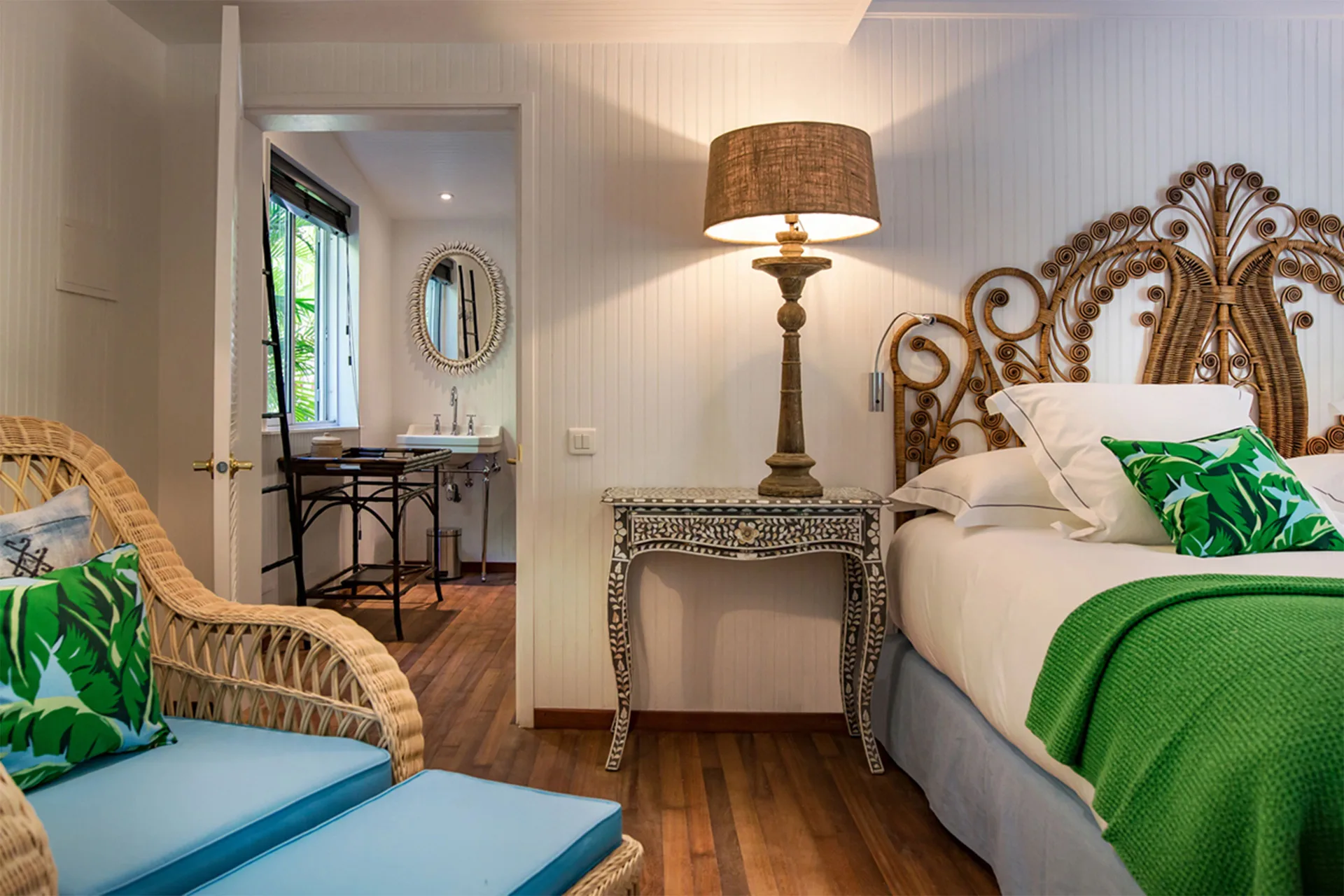 Bungalow king bed with rattan headboard and open bathroom at GYP SEA Saint Barth.