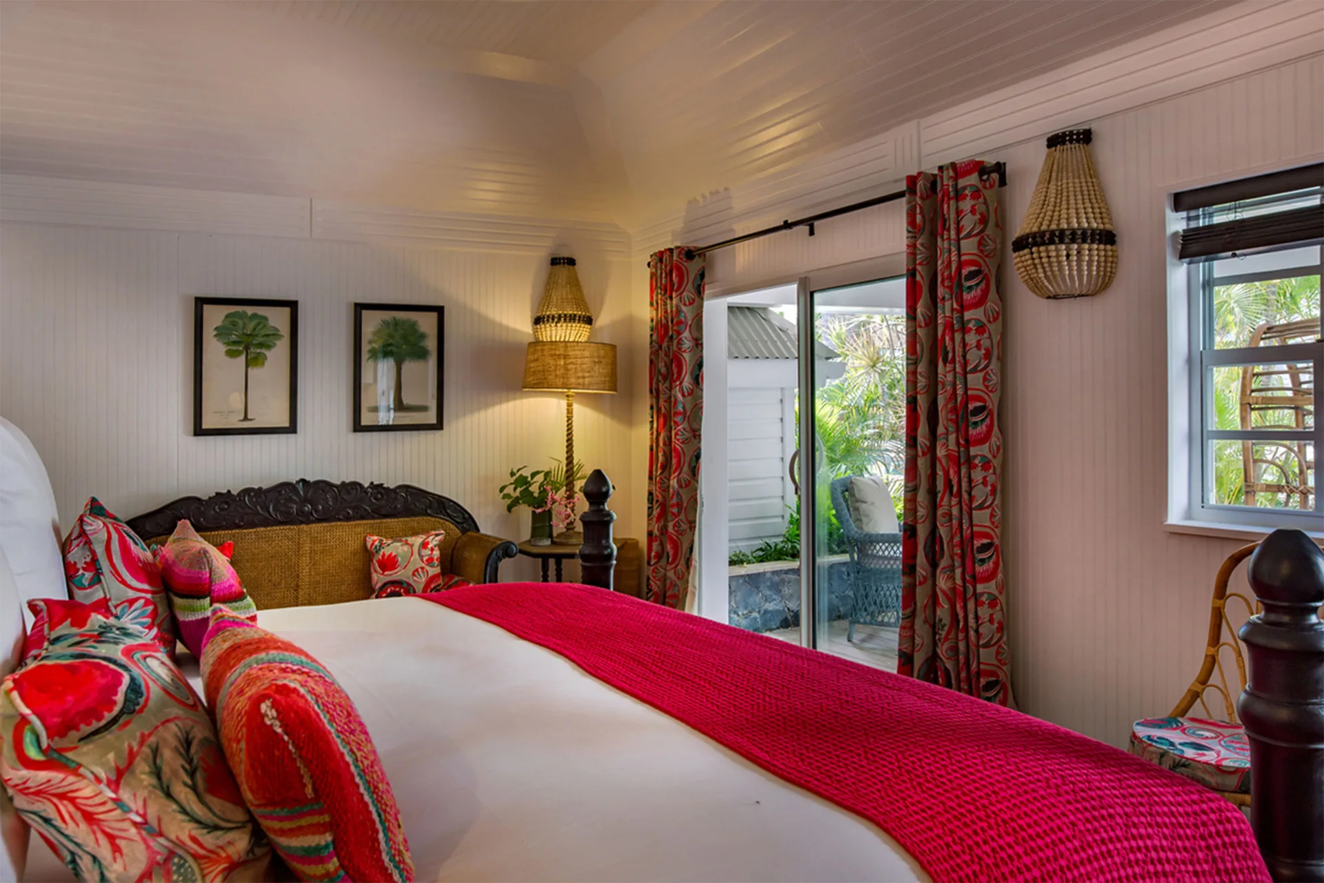 Bungalow king bed with red accents and terrace doors at GYP SEA Saint Barth.