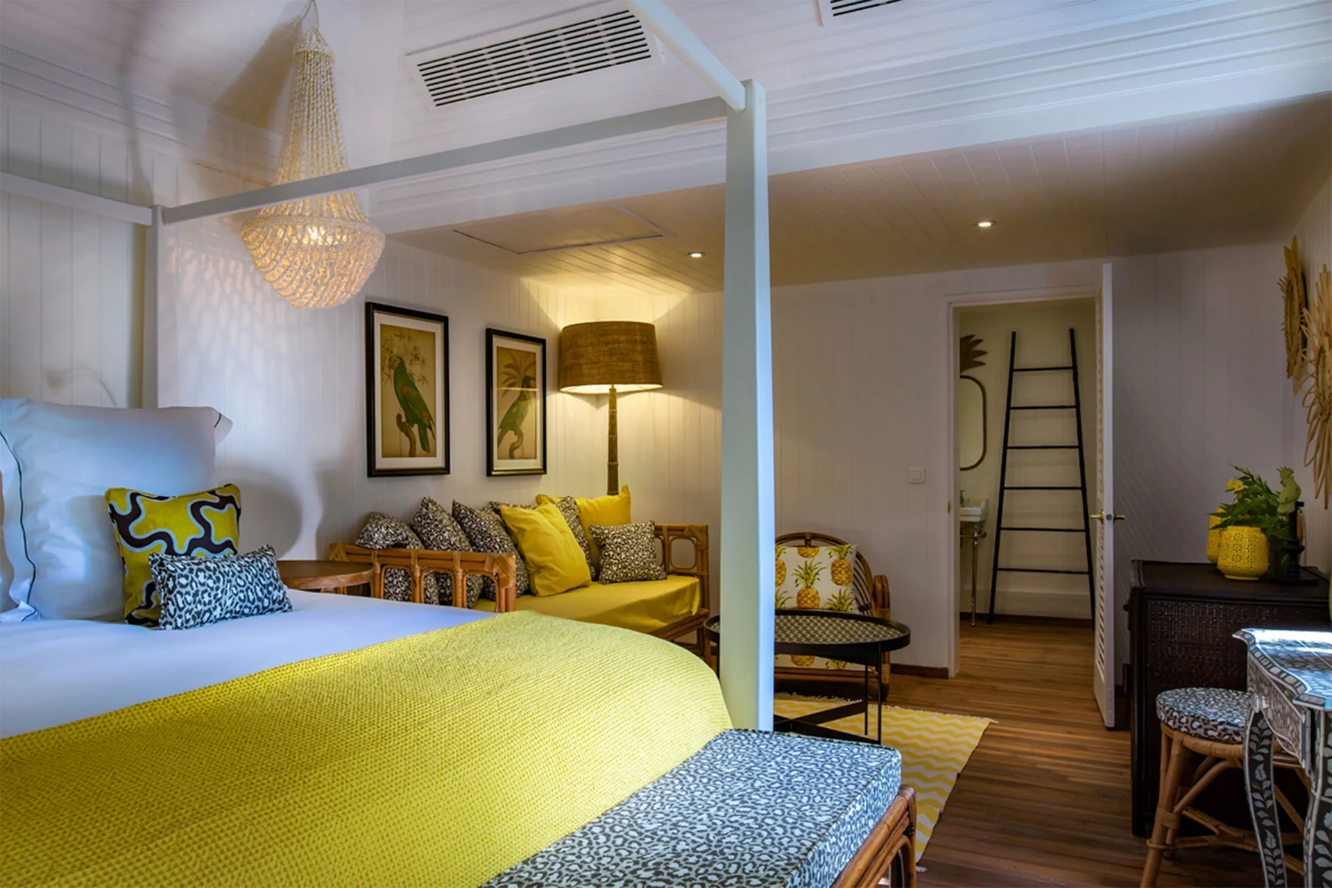 Bungalow king bed with yellow throw and sitting area at GYP SEA Saint Barth.