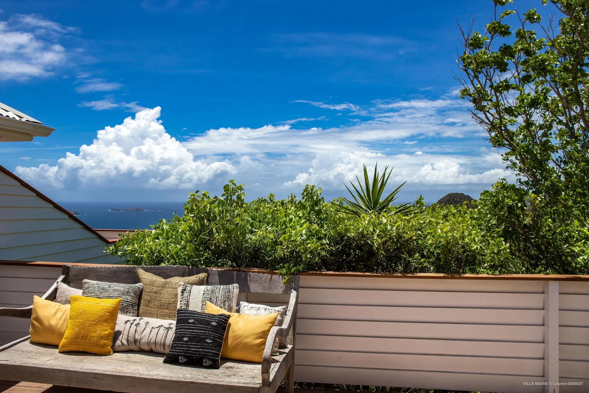 Prestige Caribbean Bungalow terrace bench with sea view beyond greenery at GYP SEA Saint Barth.